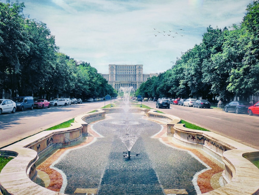 a fountain in the middle of a street with a building in the background