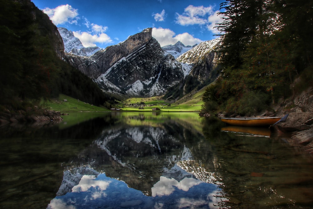 a lake surrounded by mountains with a boat in the water