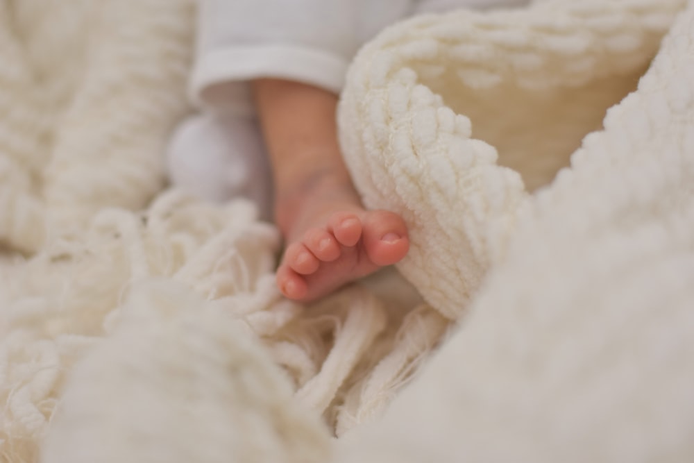 El pie de un bebé está metido debajo de una manta