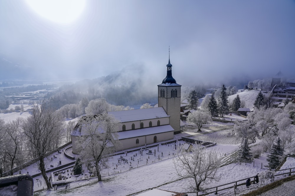 a church with a steeple surrounded by snow covered trees