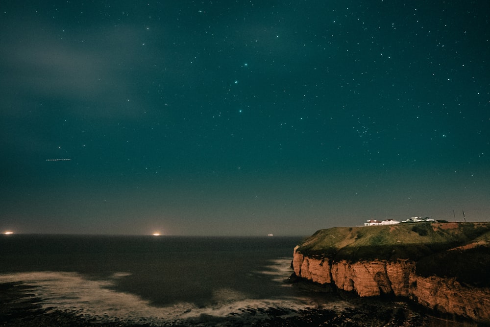 the night sky over the ocean and a cliff
