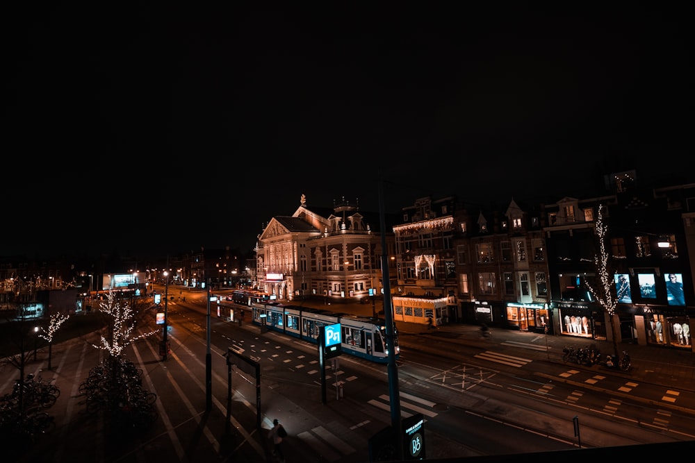 a city street at night with a train on the tracks