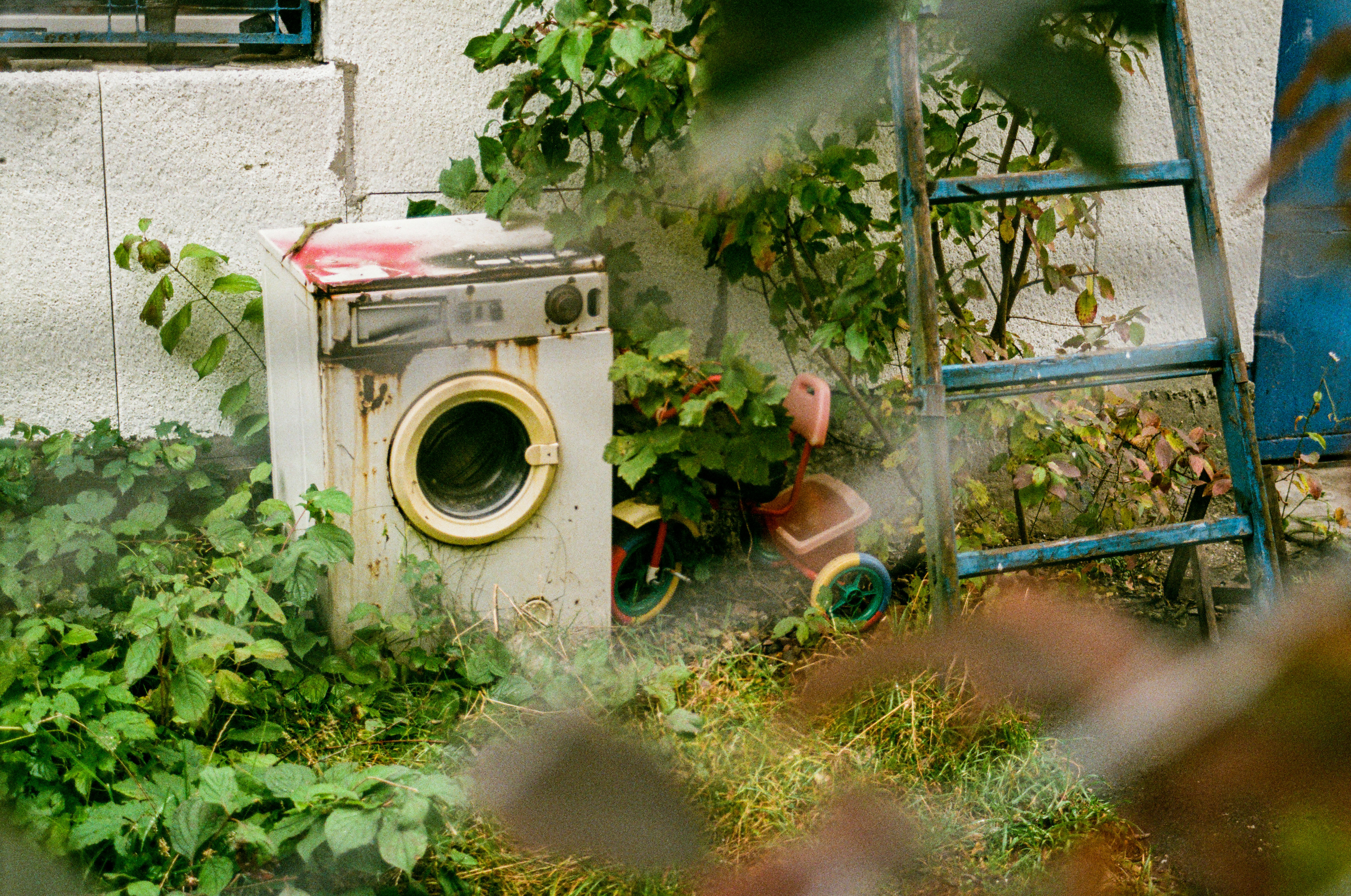 a washing machine sitting in the grass next to a ladder