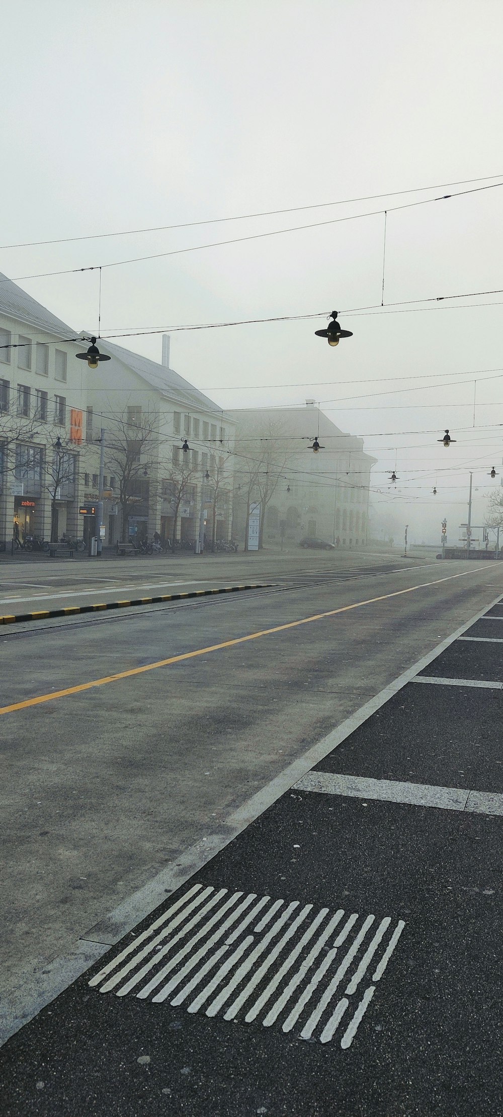 a foggy street with a few traffic lights hanging over it