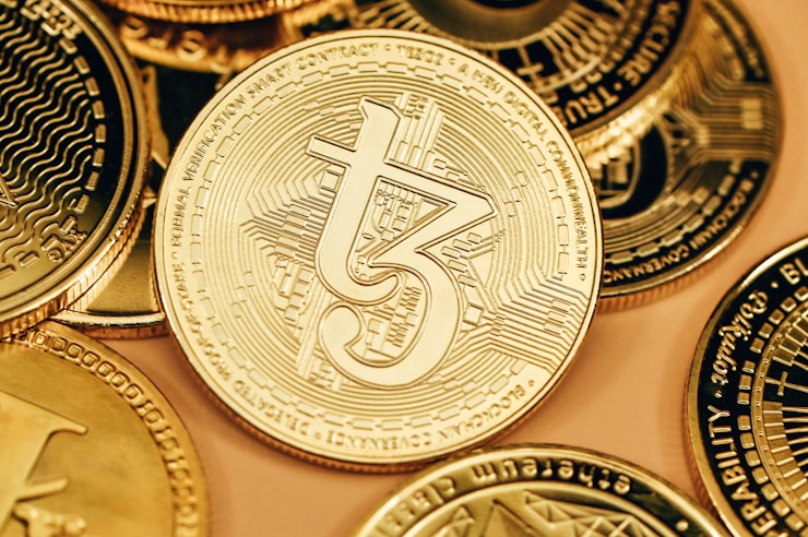 A gold Tezos coin shining among other coins