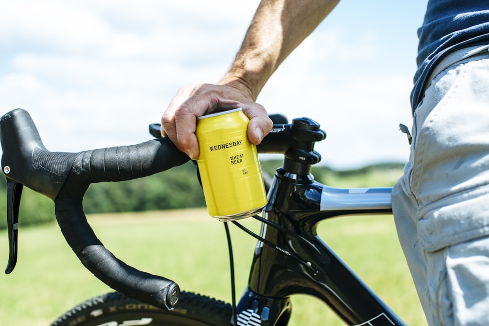 a close up of a person holding a yellow can on a bike