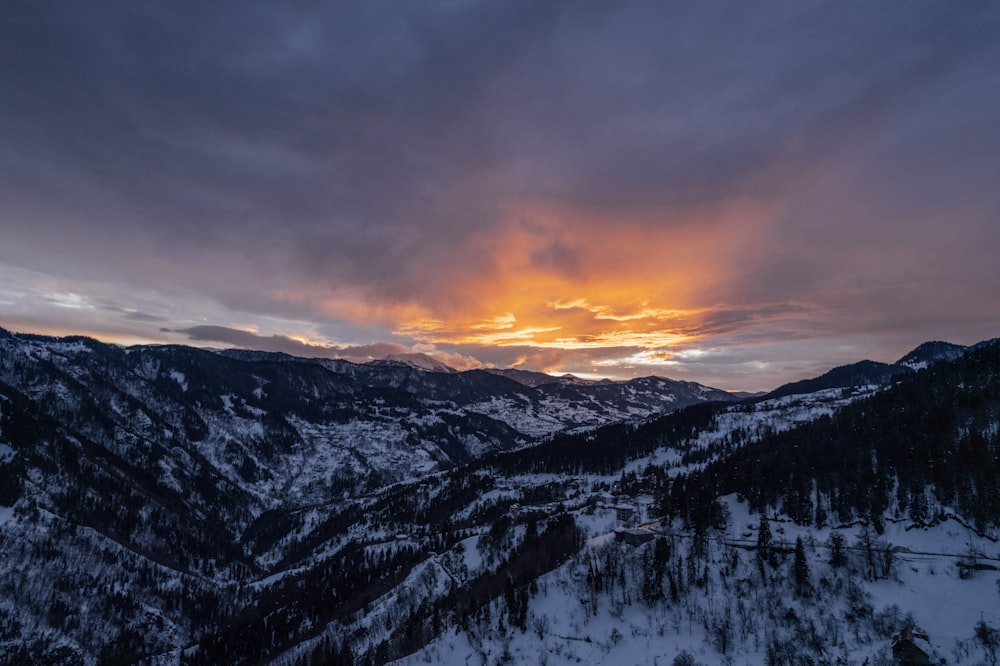 the sun is setting over a snowy mountain range