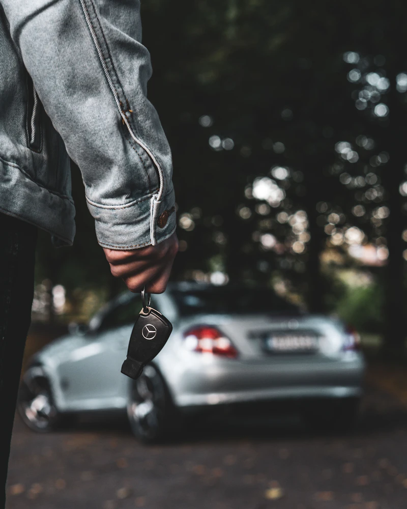 Handing over car keys next to a silver car