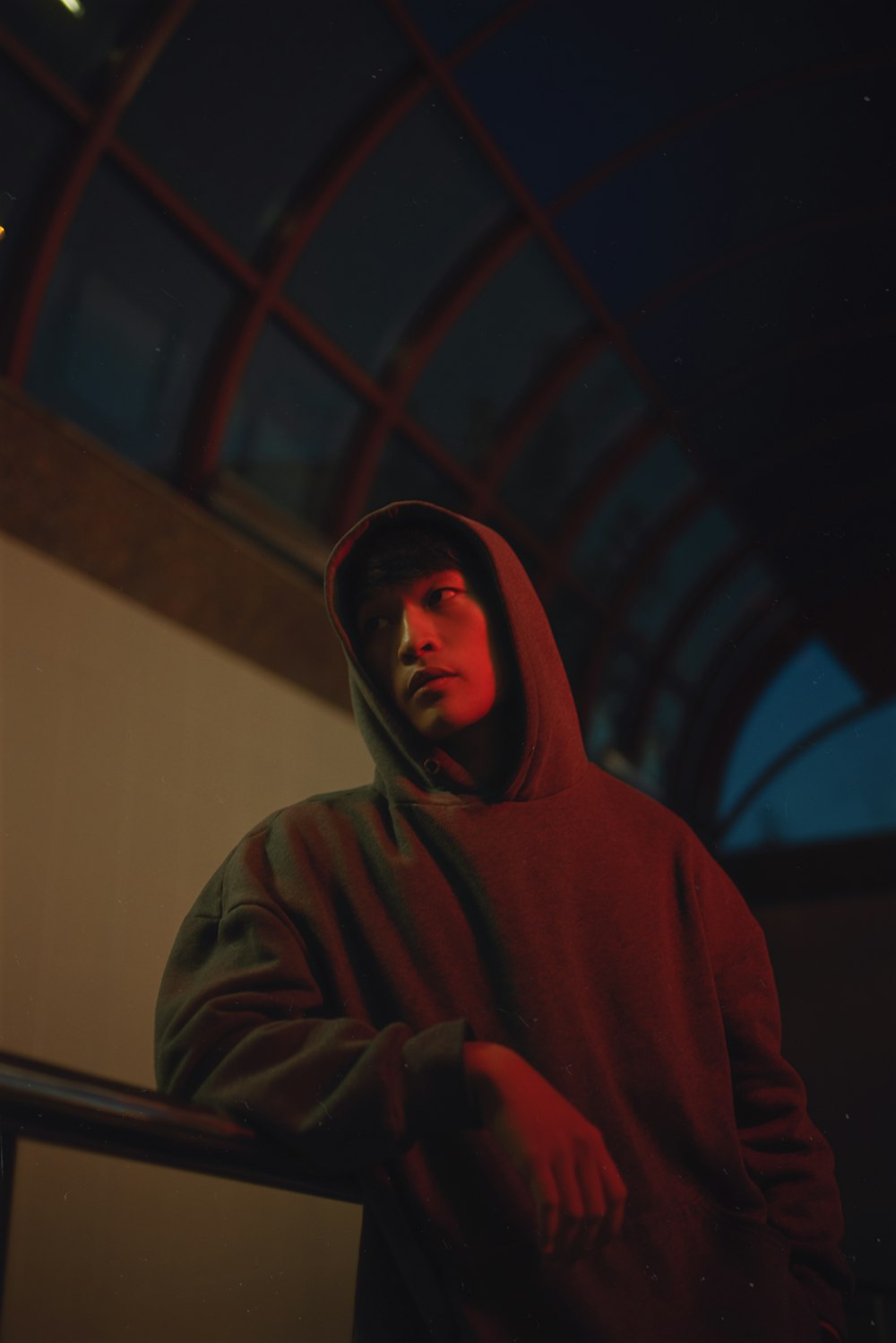 a man in a red hoodie standing in front of a building