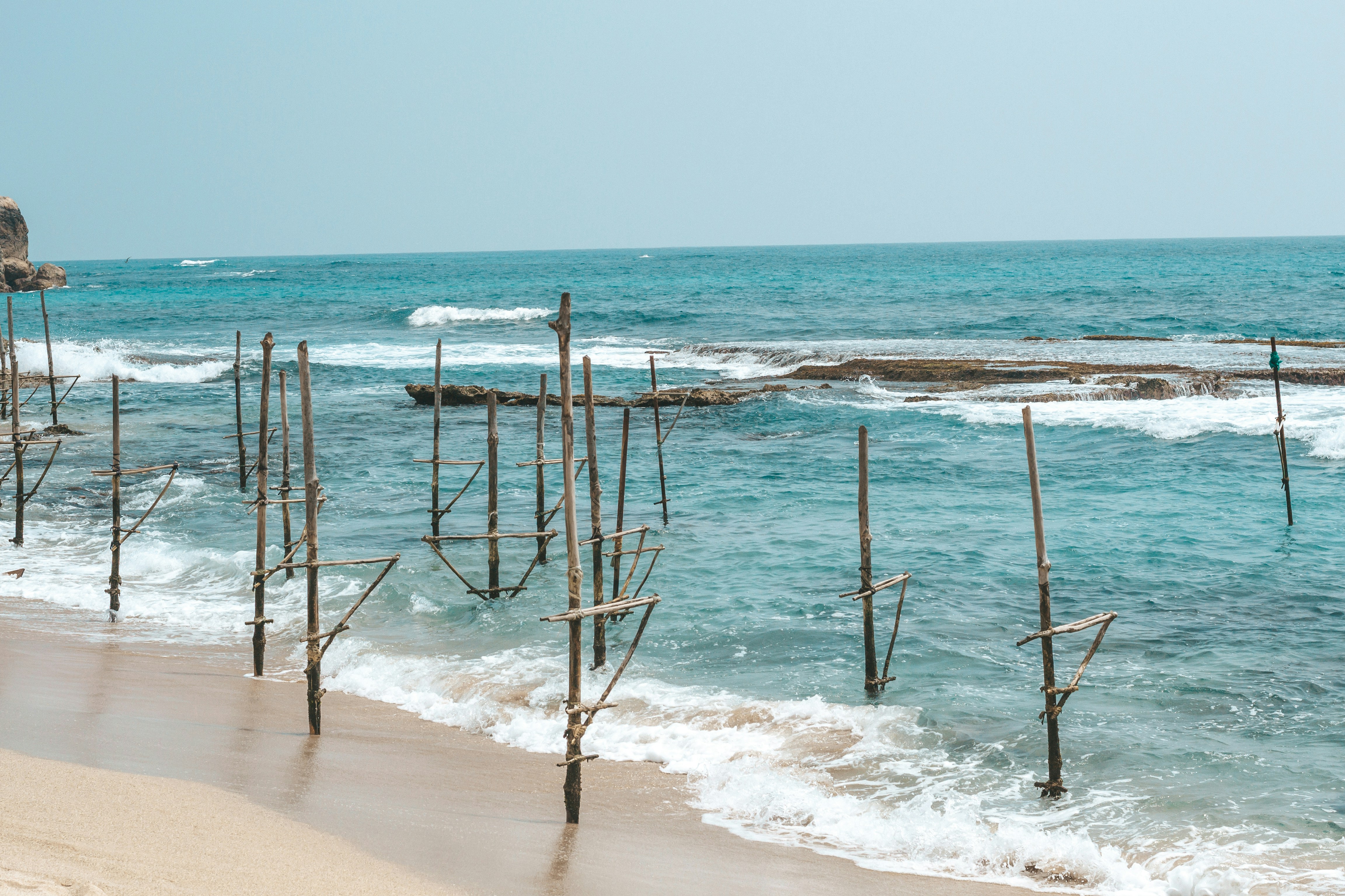 a beach with a bunch of poles sticking out of the water, 