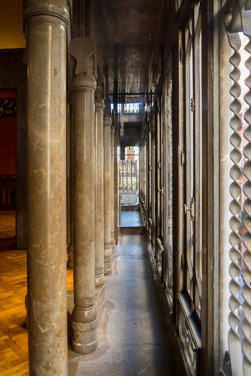 Un largo pasillo bordeado de columnas y ventanas