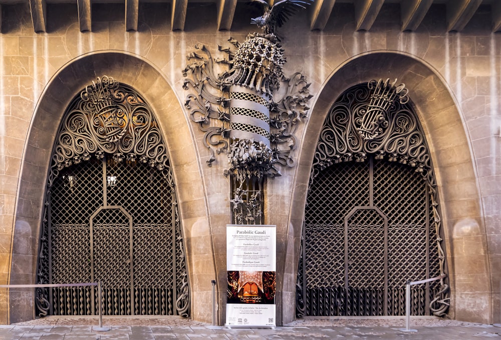 a tall building with ornate iron doors and a clock on the front of it