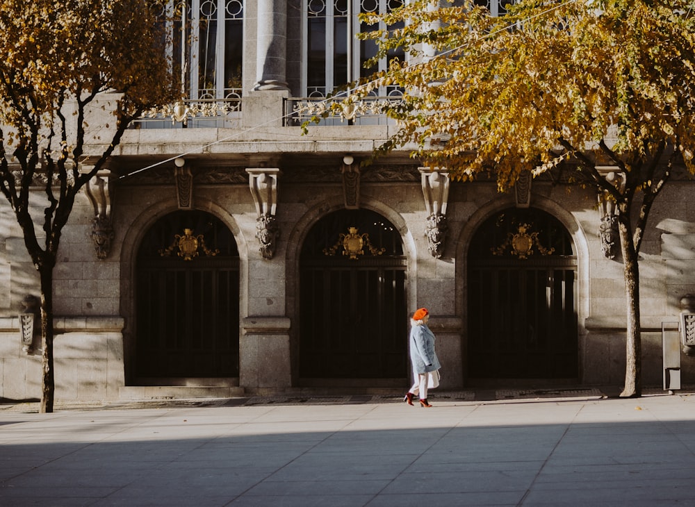 une personne marchant sur un trottoir devant un immeuble