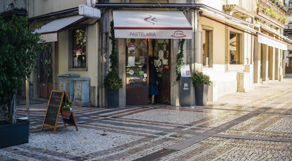 a street corner with a store front and a sign on the sidewalk