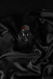 Sleek dark bottle resting on velvet fabric