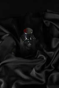 A sleek black and burgundy perfume bottle of Vesario’s Desire fragrance resting on a champagne gold surface with soft shadows.