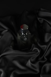 A sleek bottle of 'Stud' men's perfume with deep red and black accents on a dark textured background.