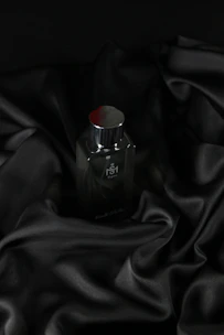 A sleek black and rose gold perfume bottle elegantly displayed on a white marble surface.