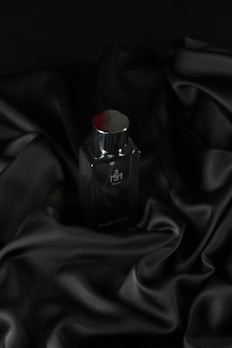 A sleek bottle of classic floral perfume resting on a soft textured fabric.