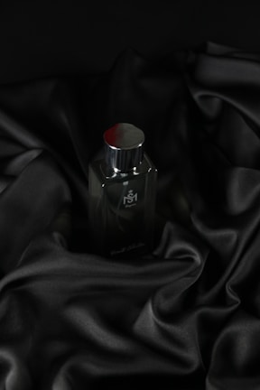 Close-up of a sleek Valentino perfume bottle next to a tailored men's jacket.