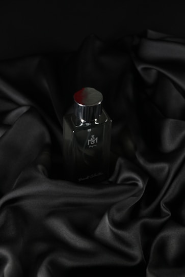 A sleek bottle of classic floral perfume resting on a soft textured fabric.