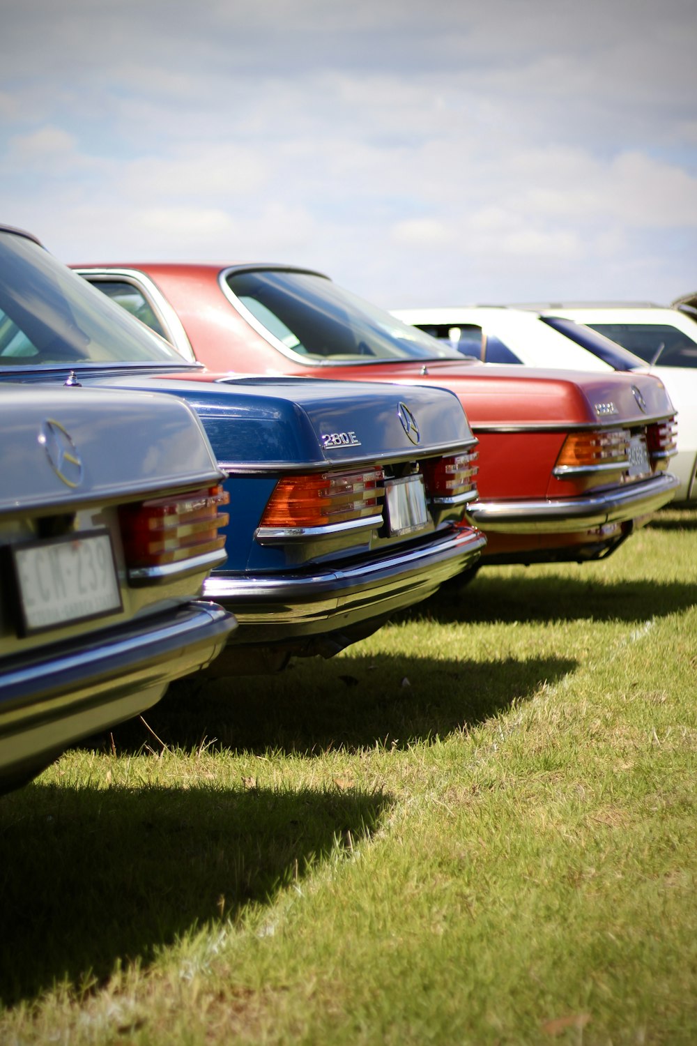 a row of parked cars sitting on top of a lush green field