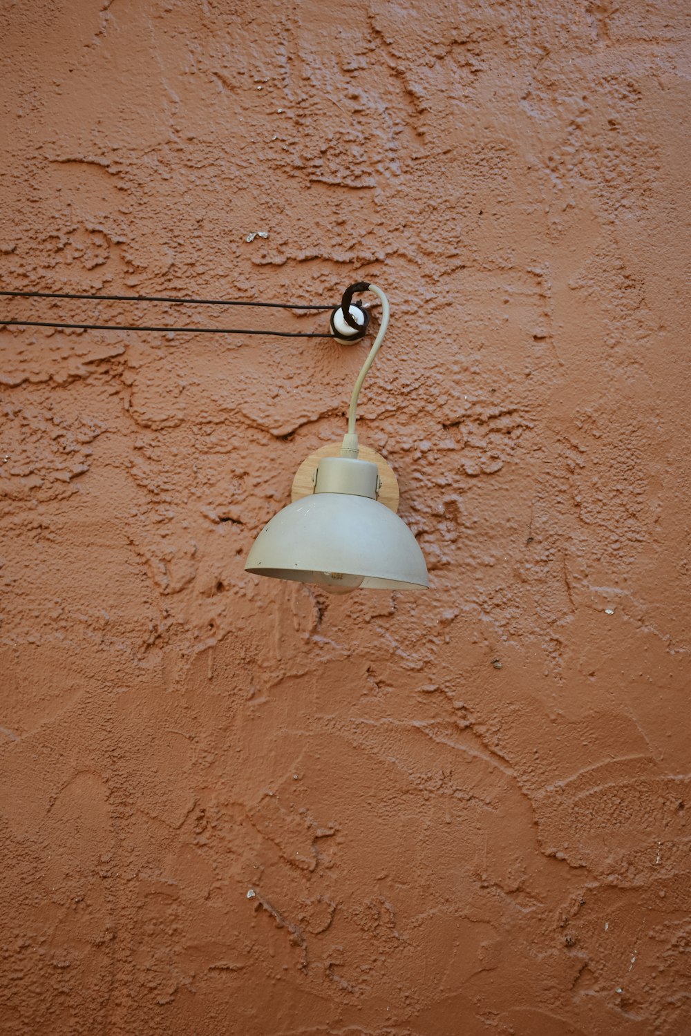 a light hanging from a wall on a wire