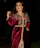 A close-up of a woman draped in a velvet burgundy dress under soft golden light, evoking Parisian night elegance.