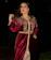 A close-up of a woman draped in a velvet burgundy dress under soft golden light, evoking Parisian night elegance.