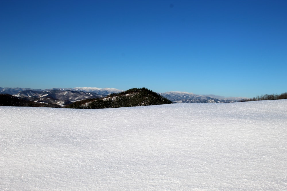 a snow covered hill with a blue sky in the background