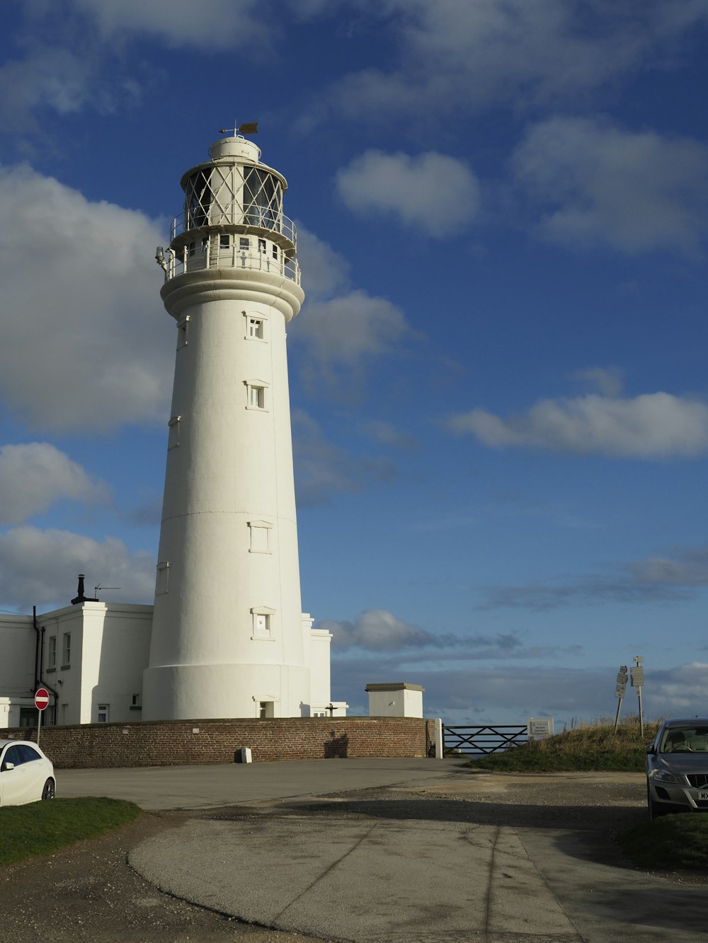 a white car parked in front of a white lighthouse