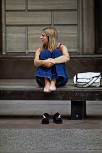 a woman sitting on a bench in front of a building