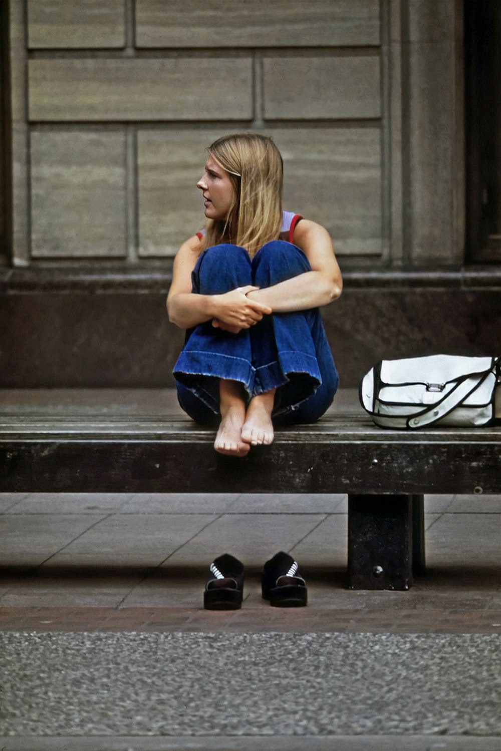 a woman sitting on a bench in front of a building
