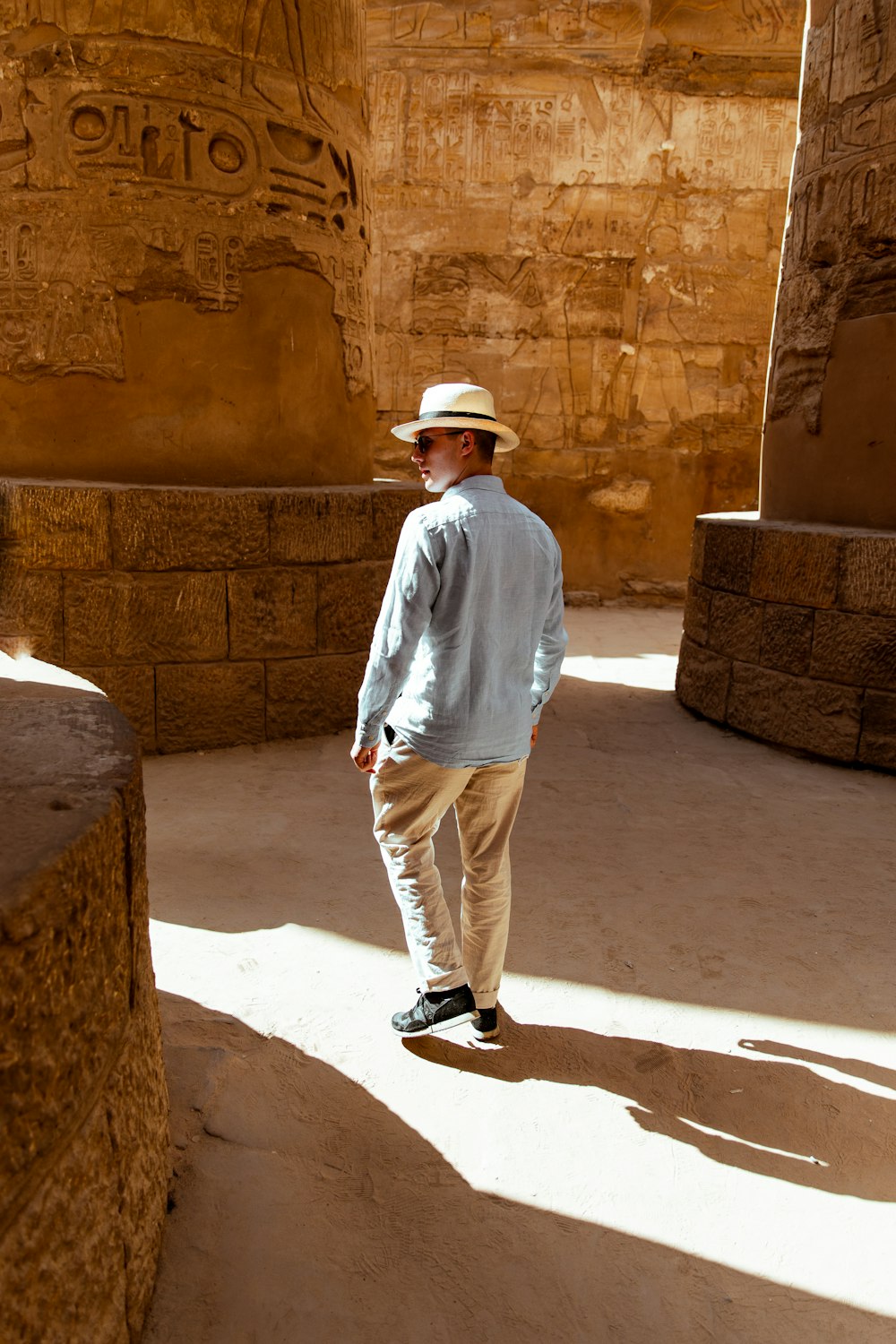 a man in a hat standing in front of a wall