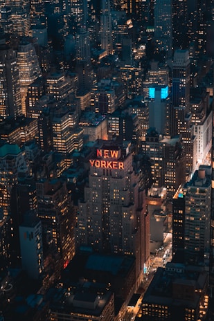 Nighttime aerial view of Manhattan with glowing building lights and busy streets.