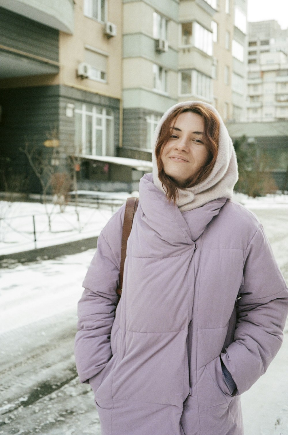 a woman standing in the snow in front of a building