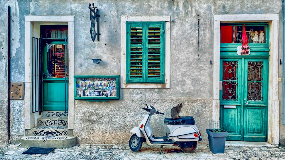 a scooter parked in front of a building with green shutters