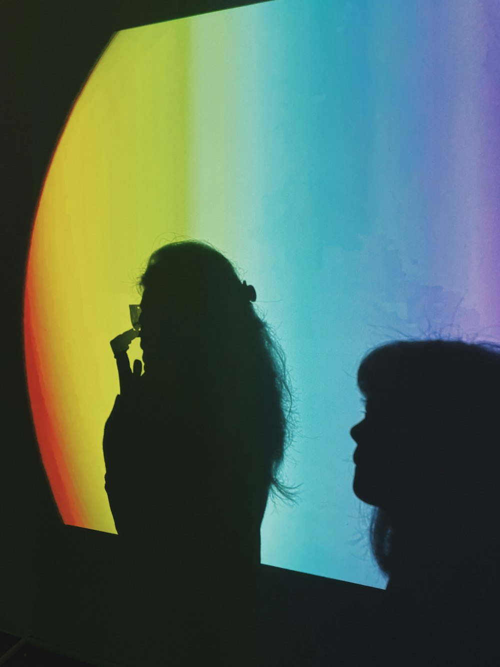 a woman standing in front of a rainbow colored wall