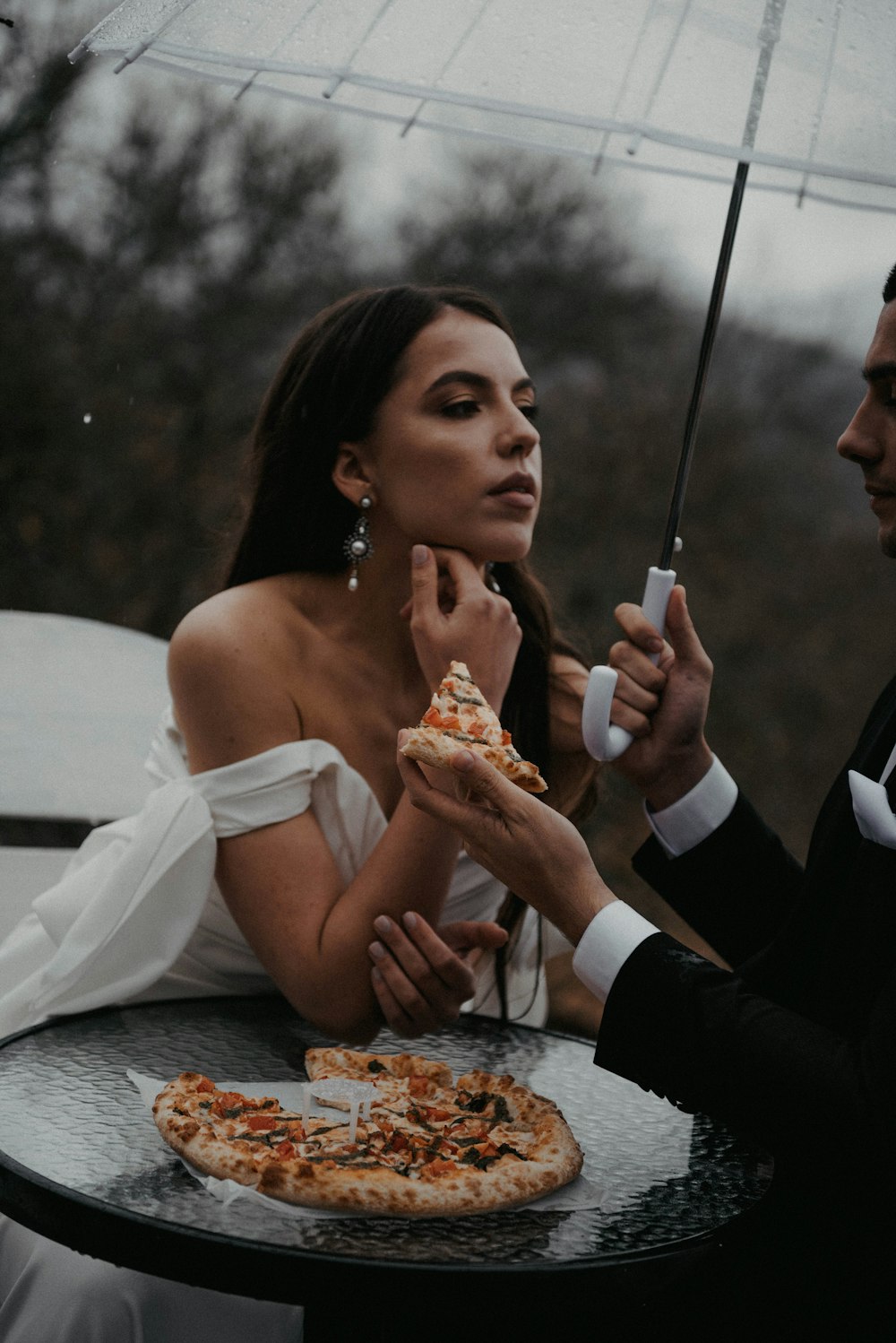 a man and a woman sitting at a table eating pizza