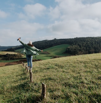 a woman standing on top of a lush green hillside