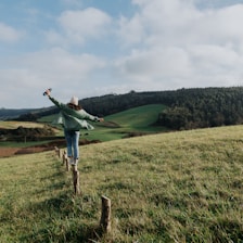 a woman standing on top of a lush green hillside