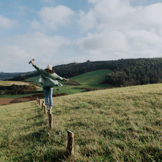 a woman standing on top of a lush green hillside