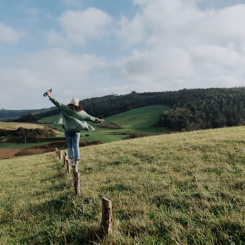 a woman standing on top of a lush green hillside