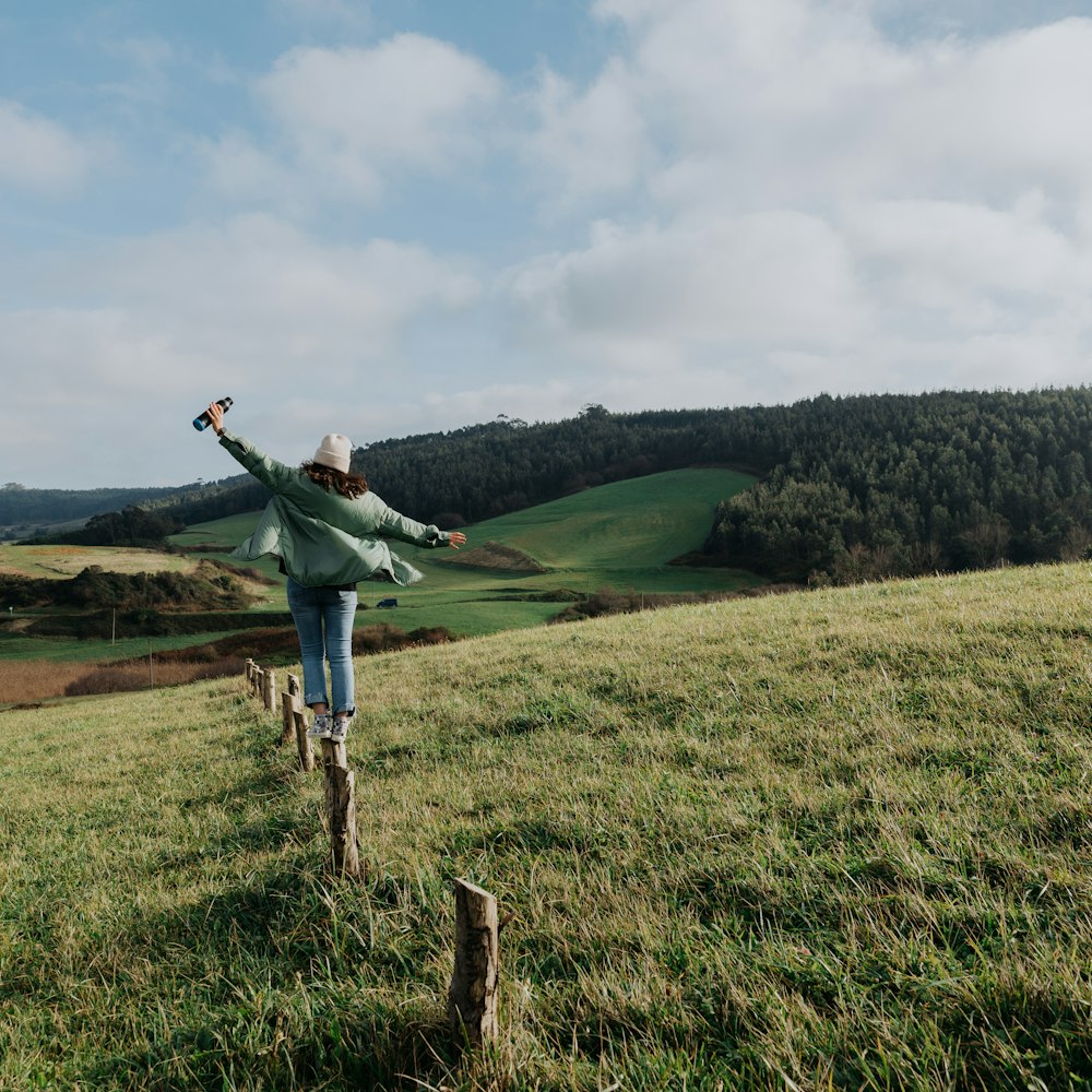 a woman standing on top of a lush green hillside