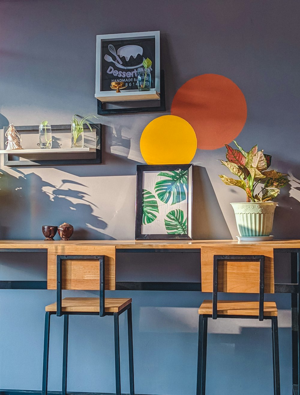 a wooden table topped with two chairs next to a wall