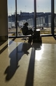Smiling traveler holding a plane ticket at a sunny airport terminal