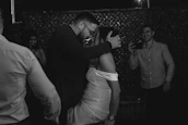 Candid photo of guests laughing and dancing at a wedding reception.