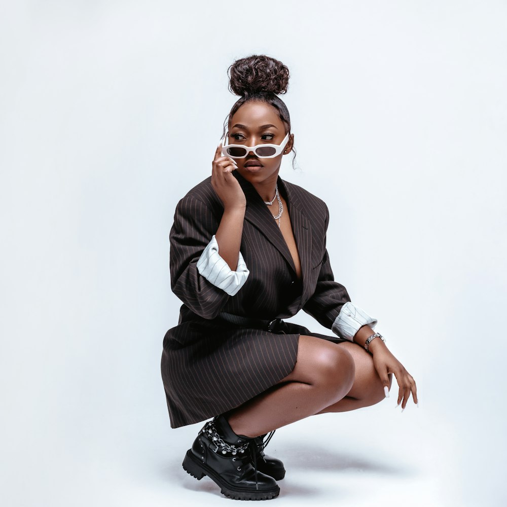 a woman sitting on the ground with a pair of sunglasses on her face