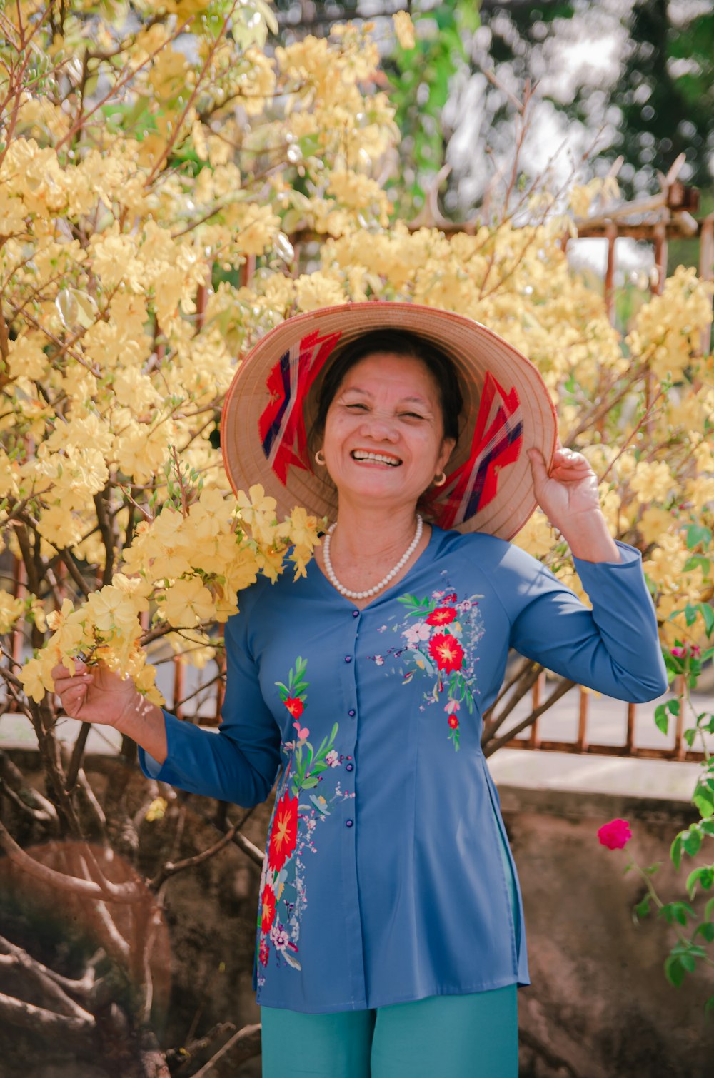 a woman wearing a hat standing in front of a tree