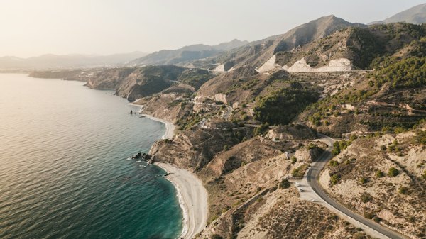 The coast road winding along the mountainside, from above — Nerja, Spain